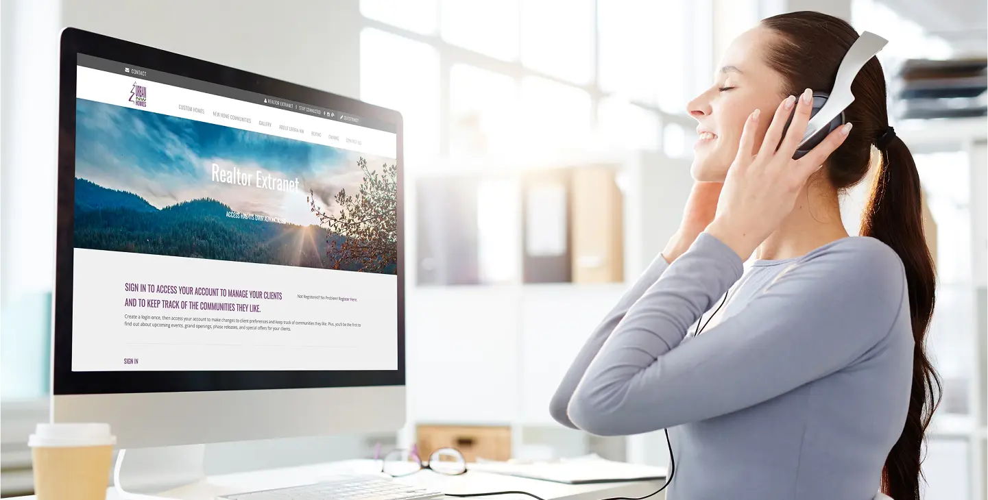 Lady holding her headphones on her ears at her computer desk