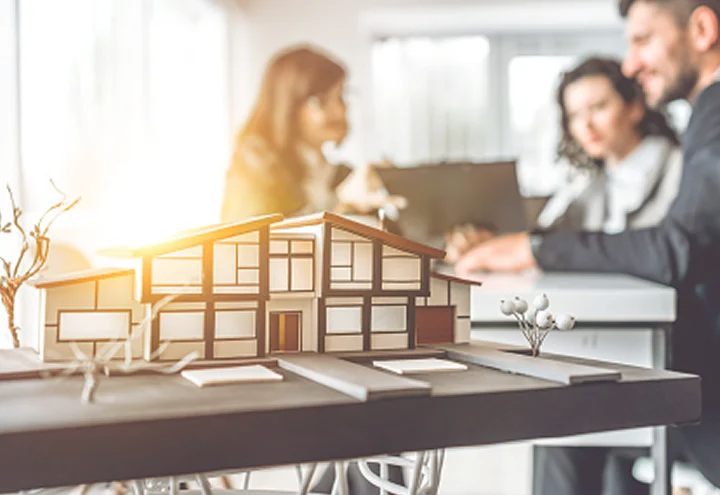 Architectural model of a modern home with a team collaborating in the background